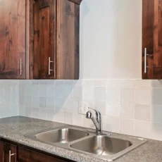 aluminum kitchen sink and white tile backsplash