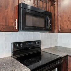 close up of kitchen stove and black microwave